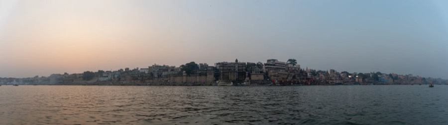 Panorama of the Varanasi ghats and riverfront skyline seen from the Ganges in flat dusk haze