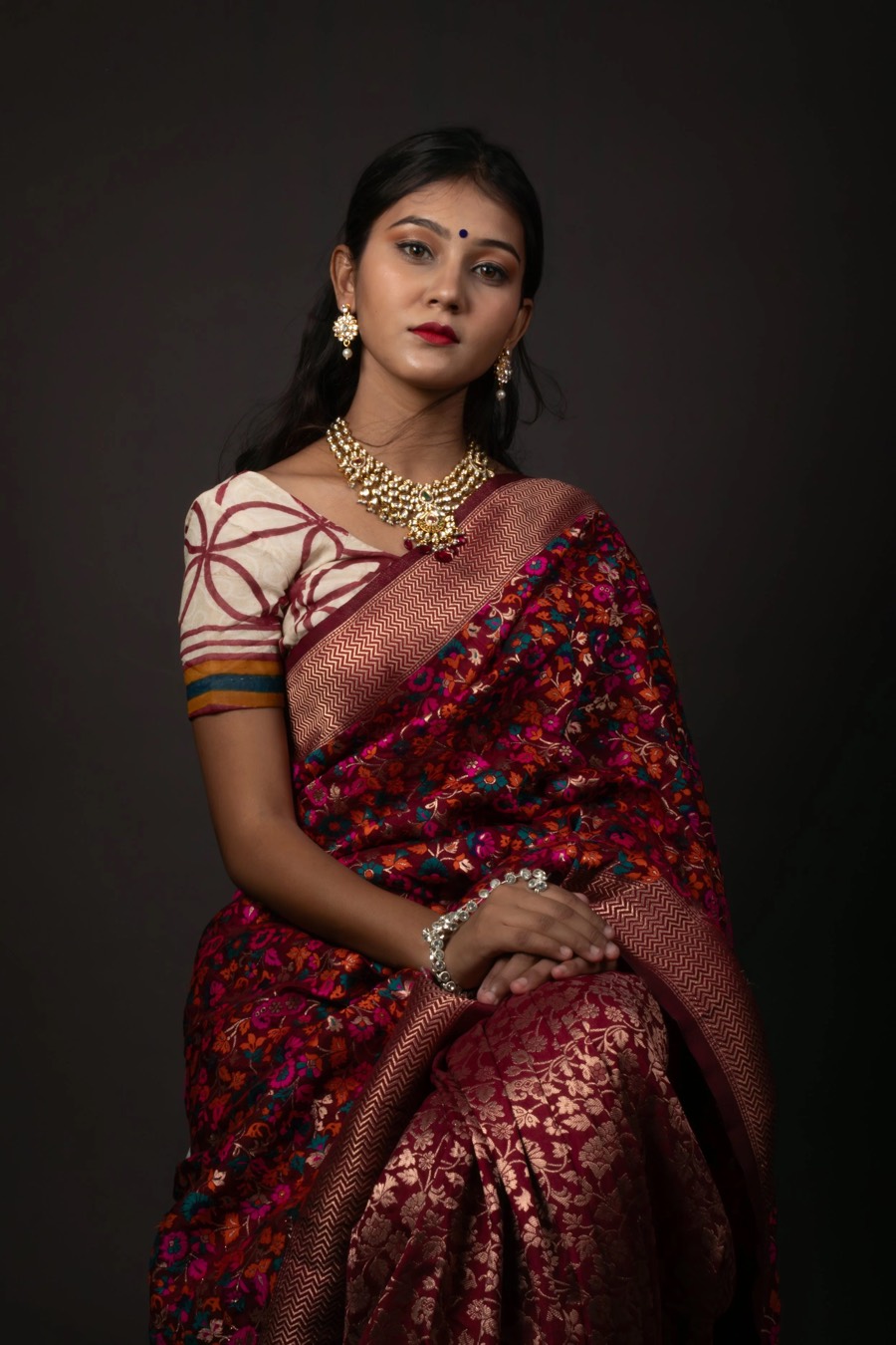 Maroon banarasi saree with gold zari in a studio three-quarter frame, portrait photography by Curtain Drop Media