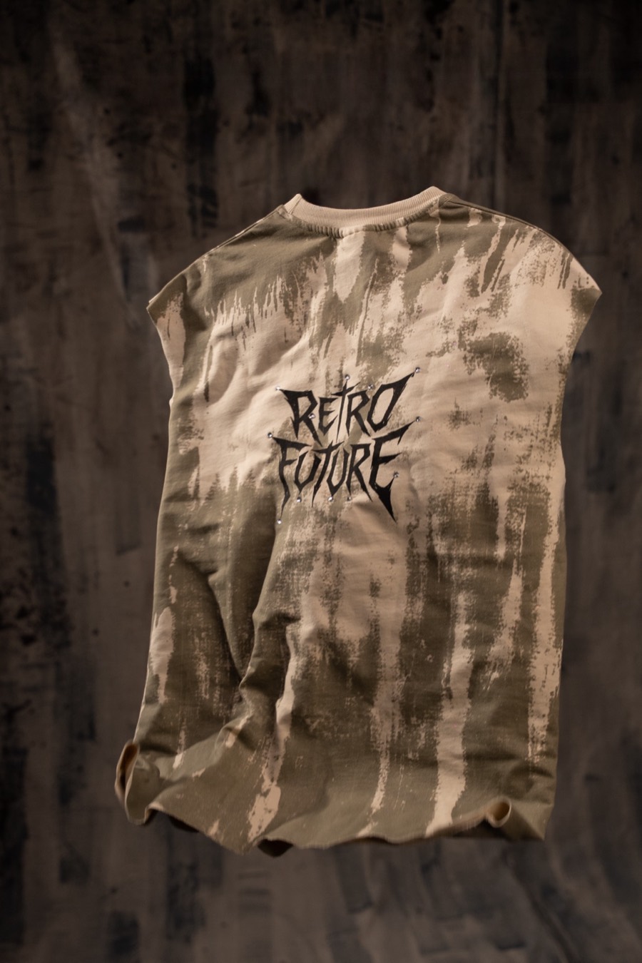 Distressed khaki sleeveless tee laid flat on dark concrete, RETRO FUTURE graphic across the chest